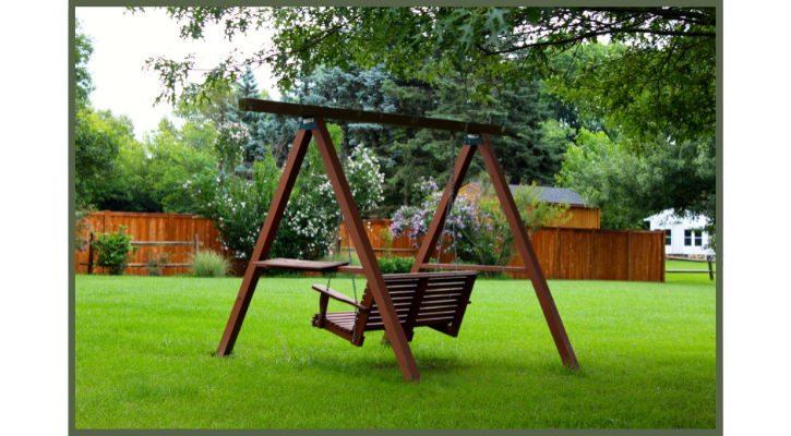 backyard swing under a tree over top of a green lawn