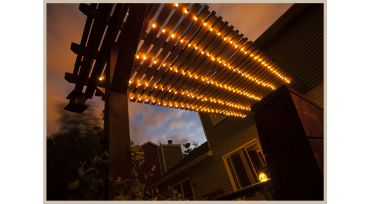 string lights through a backyard pergola at night