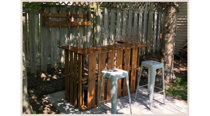 backyard bar built out of wood pallets in the shade with two metal chairs